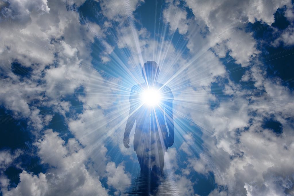 Une silhouette humaine stylisée et épurée se détache sur un fond de ciel bleu parsemé de nuages, avec des rayons de lumière éclatants qui semblent irradier du centre de la forme, créant une image puissante d'inspiration ou de révélation spirituelle.